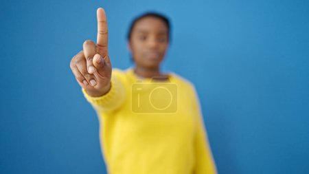 Foto de Mujer afroamericana diciendo no con el dedo sobre fondo azul aislado - Imagen libre de derechos