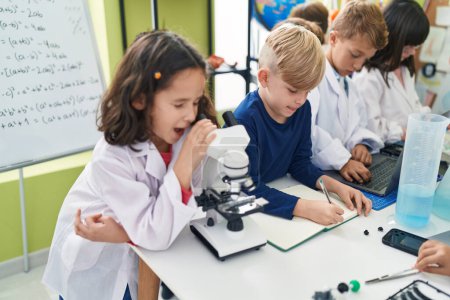 Photo for Group of kids students using microscope writing on notebook at laboratory classroom - Royalty Free Image