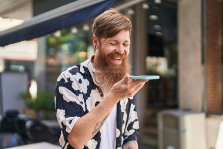 Téléchargez les photos : Jeune rousse homme souriant confiant parler sur le smartphone à la rue - en image libre de droit