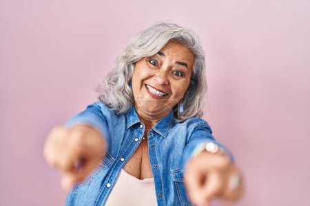 Photo for Middle age woman with grey hair standing over pink background pointing to you and the camera with fingers, smiling positive and cheerful - Royalty Free Image