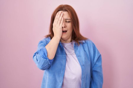 Photo for Young hispanic woman with red hair standing over pink background yawning tired covering half face, eye and mouth with hand. face hurts in pain. - Royalty Free Image