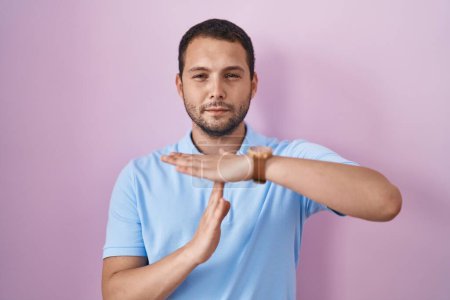 Photo for Hispanic man standing over pink background doing time out gesture with hands, frustrated and serious face - Royalty Free Image