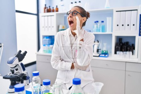 Photo for Young woman working at scientist laboratory clueless and confused with open arms, no idea and doubtful face. - Royalty Free Image