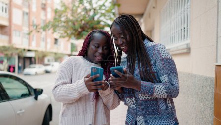Photo for Two african american friends smiling confident using smartphone at street - Royalty Free Image