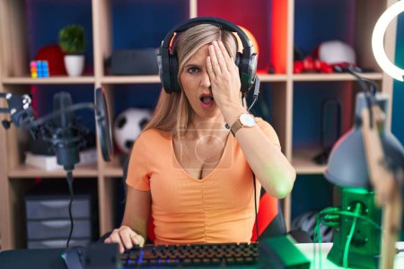 Foto de Mujer joven jugando videojuegos bostezando cansada cubriendo media cara, ojo y boca con la mano. cara duele en el dolor. - Imagen libre de derechos