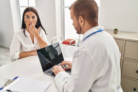 Photo for Young hispanic woman at the doctor covering mouth with hand, shocked and afraid for mistake. surprised expression - Royalty Free Image