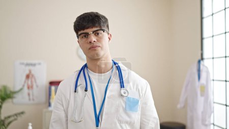 Photo for Young hispanic man doctor standing with serious expression at clinic - Royalty Free Image