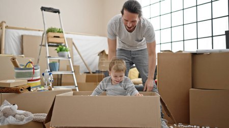 Photo for Father and son playing with cardboard box at new home - Royalty Free Image