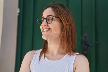 Téléchargez les photos : Jeune femme souriante et confiante portant des lunettes dans la rue - en image libre de droit