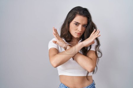 Photo for Young teenager girl standing over white background rejection expression crossing arms doing negative sign, angry face - Royalty Free Image