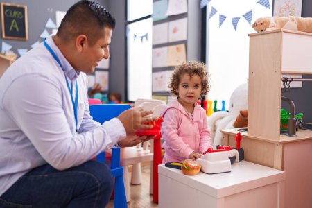 Photo for Hispanic man and girl playing supermarket game sitting on table at kindergarten - Royalty Free Image