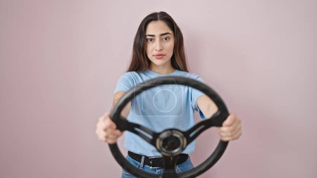 Photo for Young beautiful hispanic woman using steering wheel as a driver over isolated pink background - Royalty Free Image