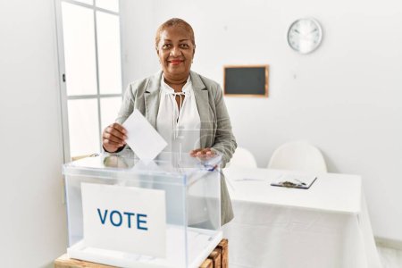 Photo for Senior african american woman smiling confident voting at charity center - Royalty Free Image