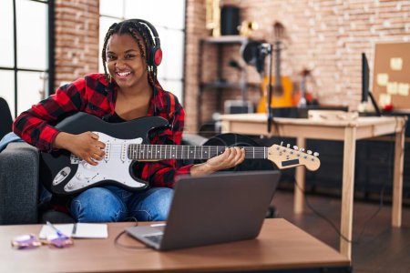 Téléchargez les photos : Africaine américaine musicien ayant cours de guitare électrique en ligne au studio de musique - en image libre de droit