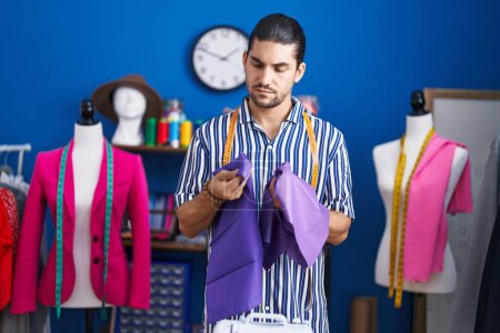 Photo for Young hispanic man tailor holding cloths at sewing studio - Royalty Free Image