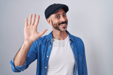 Téléchargez les photos : Homme hispanique avec barbe debout sur fond isolé renonçant à dire bonjour heureux et souriant, geste de bienvenue amical - en image libre de droit