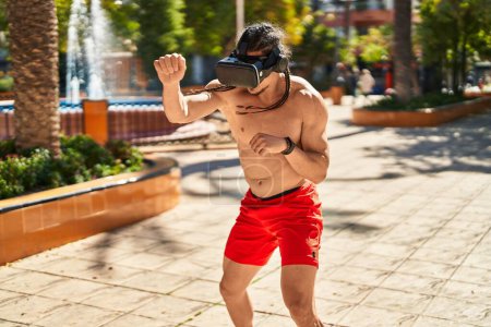 Foto de Hombre joven usando gafas de realidad virtual boxeo en el parque - Imagen libre de derechos