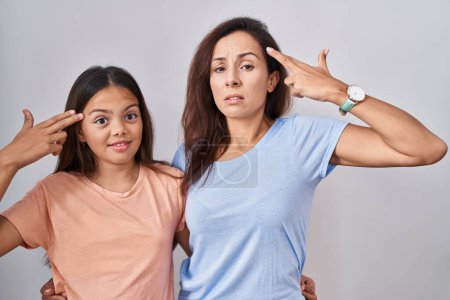 Photo for Young mother and daughter standing over white background shooting and killing oneself pointing hand and fingers to head like gun, suicide gesture. - Royalty Free Image