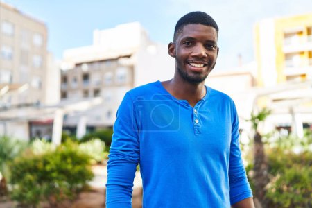 Téléchargez les photos : Jeune homme afro-américain souriant confiant debout dans la rue - en image libre de droit