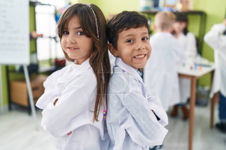 Foto de Adorable niño y niña estudiante sonriendo confiado de pie con los brazos cruzados gesto en el aula de laboratorio - Imagen libre de derechos