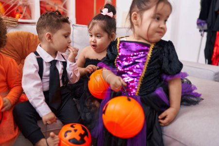 Foto de Grupo de niños con disfraz de Halloween comiendo caramelos en casa - Imagen libre de derechos