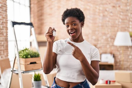 Téléchargez les photos : Femme afro-américaine tenant les clés de la nouvelle maison souriant heureux pointant avec la main et le doigt - en image libre de droit
