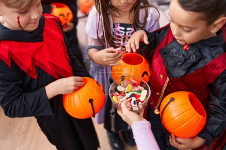 Foto de Grupo de niños con disfraz de Halloween recibiendo caramelos en casa - Imagen libre de derechos