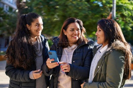 Trzy kobiety matka i córki za pomocą smartfona w parku