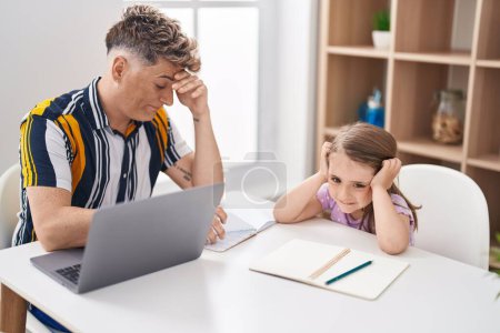 Foto de Padre e hija padre e hija estresados usando portátil estudiando en casa - Imagen libre de derechos