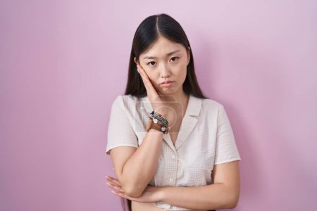 Photo for Chinese young woman standing over pink background thinking looking tired and bored with depression problems with crossed arms. - Royalty Free Image