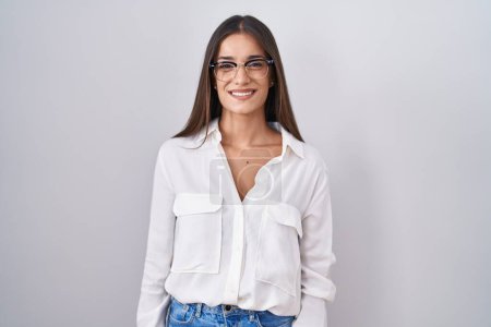 Téléchargez les photos : Jeune femme brune portant des lunettes avec un sourire heureux et cool sur le visage. chanceux. - en image libre de droit