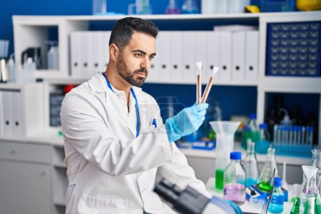 Photo for Young hispanic man scientist holding test tubes at laboratory - Royalty Free Image