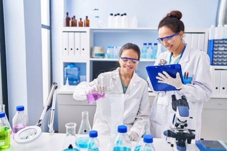 Foto de Mujer y niña vistiendo uniforme científico trabajando en el laboratorio - Imagen libre de derechos