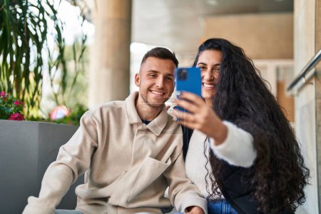 Foto de Hombre y mujer sonriendo confiados hacen selfie por el teléfono inteligente en la calle - Imagen libre de derechos