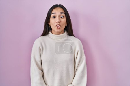 Téléchargez les photos : Jeune femme sud-asiatique debout sur fond rose faisant visage de poisson avec des lèvres, geste fou et comique. expression drôle. - en image libre de droit