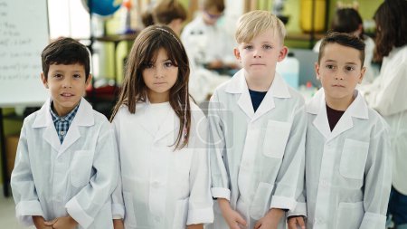 Téléchargez les photos : Groupe d'enfants scientifiques étudiants debout avec une expression détendue dans la salle de classe du laboratoire - en image libre de droit