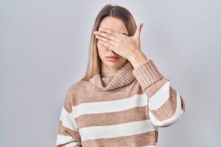 Photo for Young blonde woman wearing turtleneck sweater over isolated background covering eyes with hand, looking serious and sad. sightless, hiding and rejection concept - Royalty Free Image