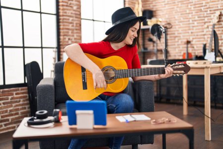 Téléchargez les photos : Young woman musician having online classical guitar lesson at music studio - en image libre de droit