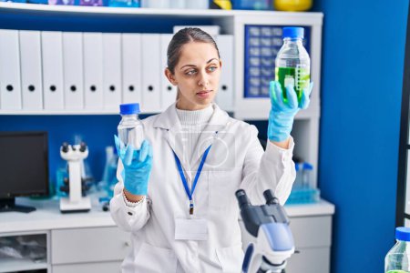 Photo for Young woman scientist holding bottles with liquid at laboratory - Royalty Free Image