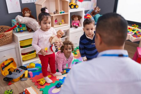 Foto de Hombre hispano y grupo de niños que tienen clase en el jardín de infantes - Imagen libre de derechos