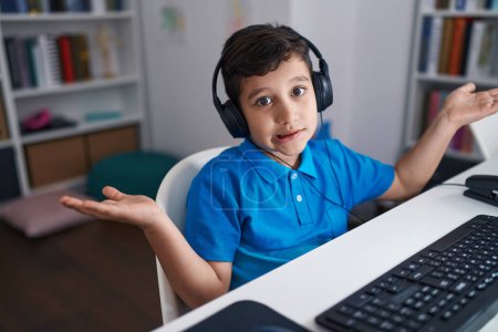 Photo for Little hispanic boy using computer laptop at the school celebrating achievement with happy smile and winner expression with raised hand - Royalty Free Image