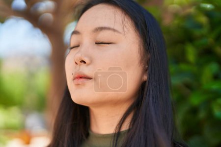 Photo for Young chinese woman scientist writing report reading book at park - Royalty Free Image