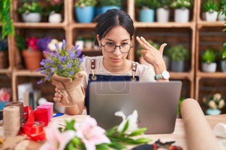 Photo for Young hispanic woman working at florist shop doing video call shooting and killing oneself pointing hand and fingers to head like gun, suicide gesture. - Royalty Free Image