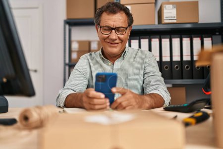 Photo for Middle age man ecommerce business worker using smartphone at office - Royalty Free Image