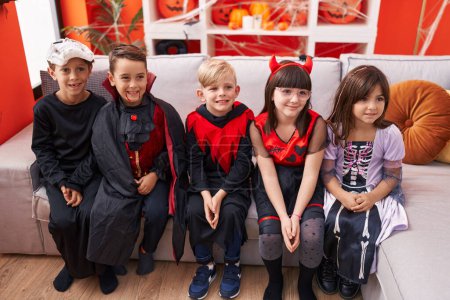 Foto de Grupo de niños con disfraz de Halloween sentados en el sofá en casa - Imagen libre de derechos