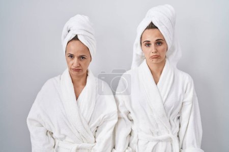 Photo for Middle age woman and daughter wearing white bathrobe and towel depressed and worry for distress, crying angry and afraid. sad expression. - Royalty Free Image