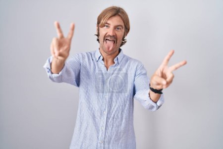 Photo for Caucasian man with mustache standing over white background smiling with tongue out showing fingers of both hands doing victory sign. number two. - Royalty Free Image