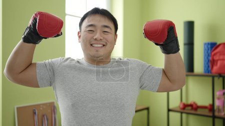 Téléchargez les photos : Jeune homme chinois souriant confiant faire un geste fort au centre sportif - en image libre de droit