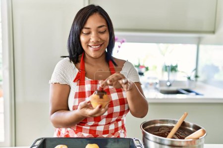Téléchargez les photos : Hispanic brunette woman preparing chocolate muffins at the kitchen - en image libre de droit