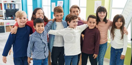 Foto de Grupo de niños estudiantes sonriendo confiados abrazándose en el aula - Imagen libre de derechos